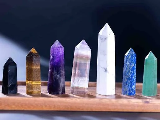 A row of polished crystal points in black, gold, violet, clear, blue and green tones